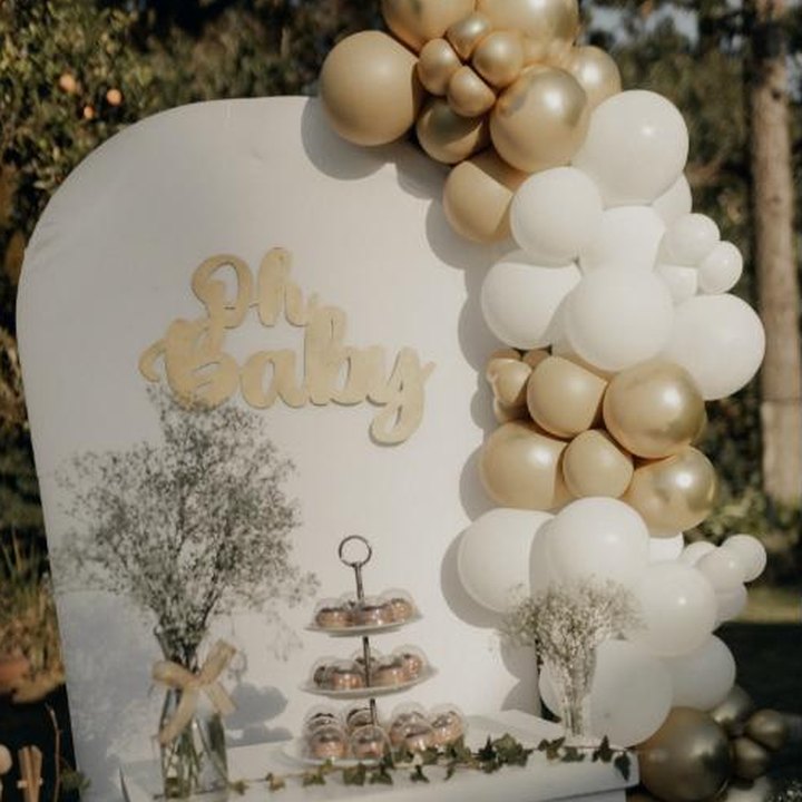 Gold and white baby shower backdrop with balloon garland